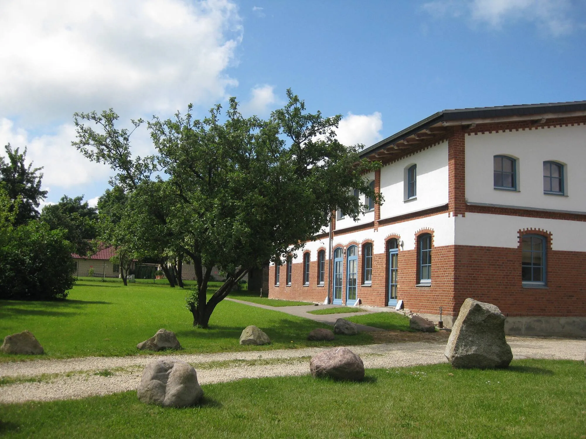 Backsteingebäude der Ferienanlage mit Obstbäumen und großer Rasenfläche