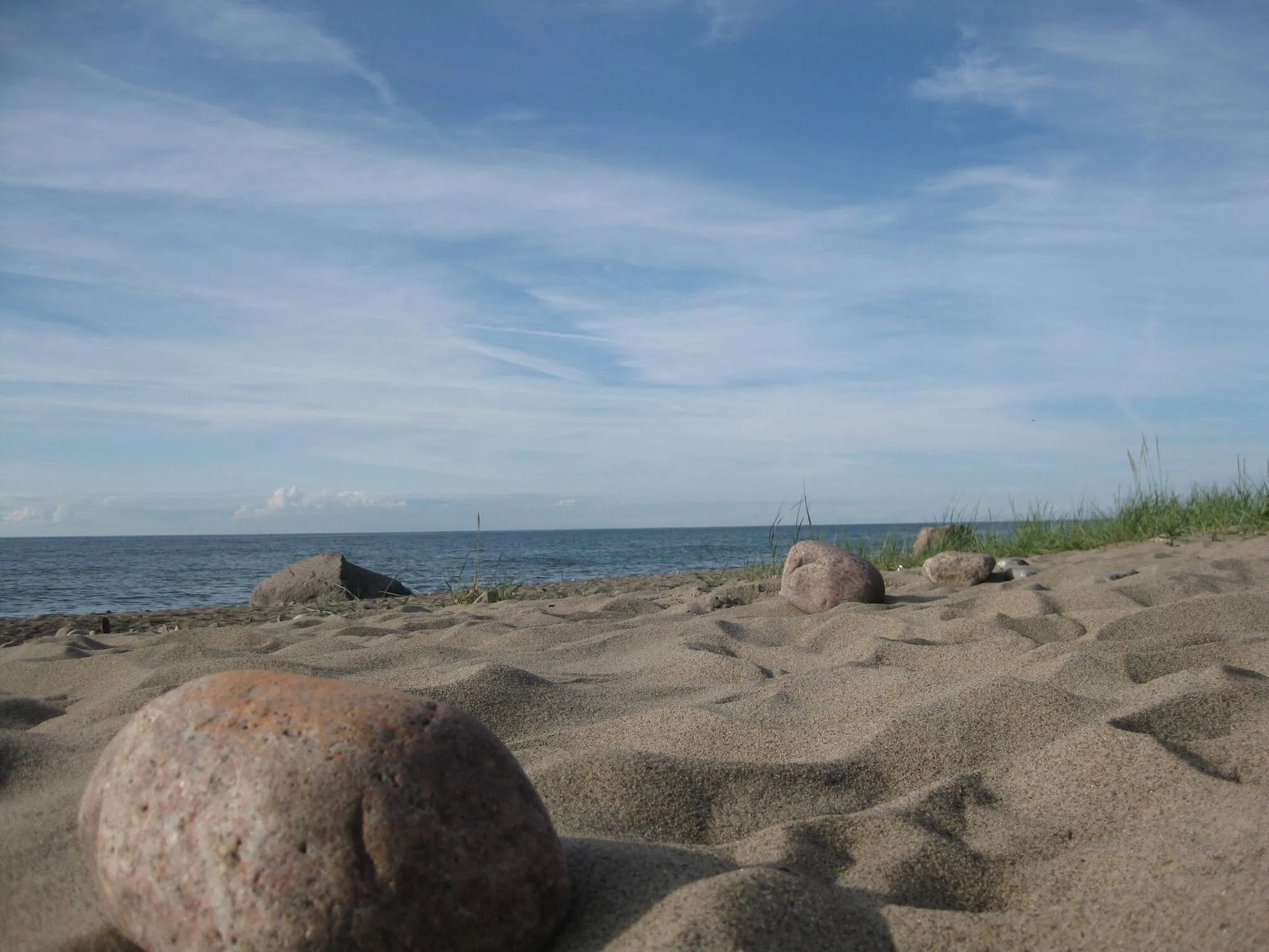 Steiniger Sandstrand mit Dünengras und ruhiger Ostsee